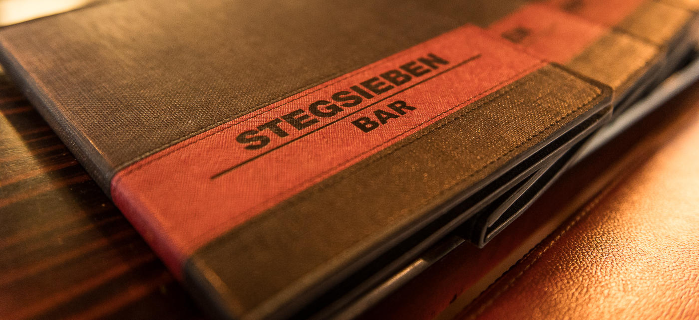 Detailansicht der Menükarte von StegSieben Bar mit geprägtem Logo.